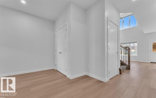 Entryway featuring wood-finish flooring, recessed lighting, white trim, and a staircase with a dark metal railing - 3025 39 Avenue, Beaumont, AB - Indoor Photo Showing Other Room