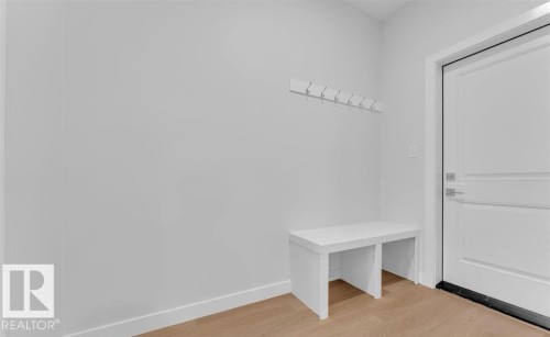 Entryway featuring light wood-finish flooring, white baseboards, and a white interior door with panel detailing and brushed nickel hardware - 3025 39 Avenue, Beaumont, AB - Indoor Photo Showing Other Room