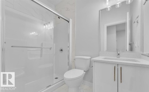 Bathroom featuring a glass-enclosed shower with subway tile surround, white vanity with integrated sink, stone-finish countertop, and a large wall-mounted mirror with overhead lighting - 3025 39 Avenue, Beaumont, AB - Indoor Photo Showing Bathroom