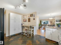 Kitchen featuring slate tile flooring, extensive white cabinetry, a built-in breakfast bar, and recessed lighting - 