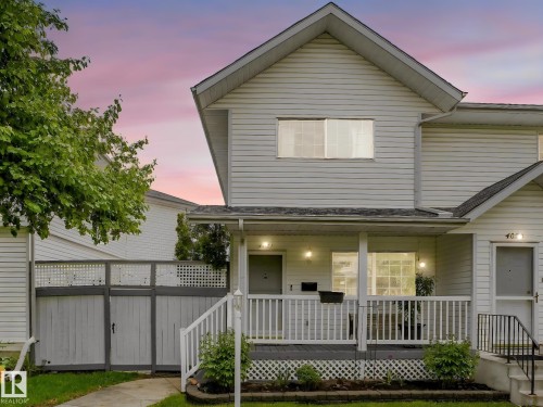 Exterior featuring white siding, a covered front porch with white railings, a front entry with a black metal handrail, and a decorative lattice skirt - 4031 38 Street, Edmonton, AB 