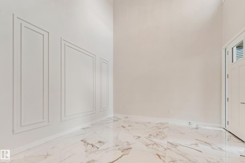 Entryway featuring high ceilings, decorative wall molding, large format marble-look tile flooring, and a white paneled door with louvered glass inserts - 4015 39 Street, Beaumont, AB - Indoor Photo Showing Other Room