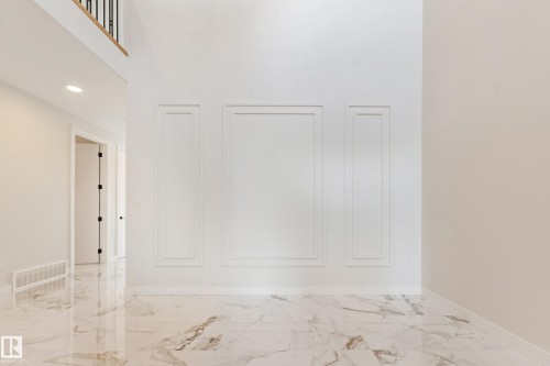 Floor-to-ceiling accent wall featuring decorative molding panels - 4015 39 Street, Beaumont, AB - Indoor Photo Showing Other Room