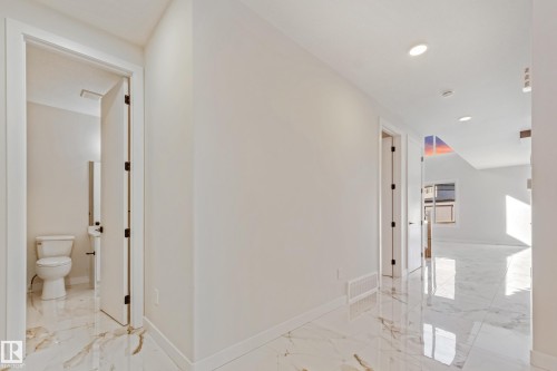 Spacious hallway featuring polished marble-look flooring, recessed ceiling lighting, and crisp white walls - 4015 39 Street, Beaumont, AB - Indoor Photo Showing Other Room