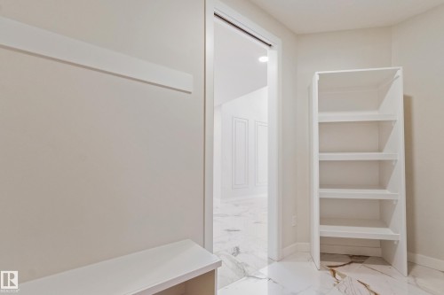 Open doorway revealing an additional room with white paneled walls and marble-style flooring - 4015 39 Street, Beaumont, AB - Indoor