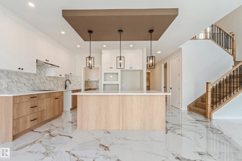 Contemporary kitchen featuring a large central island with a light wood-finish base, white countertop, and three pendant lights - 4015 39 Street, Beaumont, AB - Indoor Photo Showing Kitchen With Upgraded Kitchen