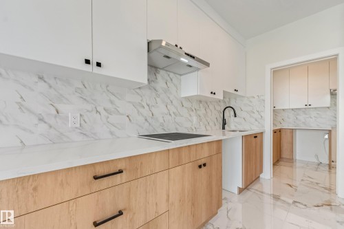 Modern kitchen featuring two-tone cabinetry with light wood-finish lower cabinets and white upper cabinets, complemented by dark hardware - 4015 39 Street, Beaumont, AB - Indoor Photo Showing Kitchen