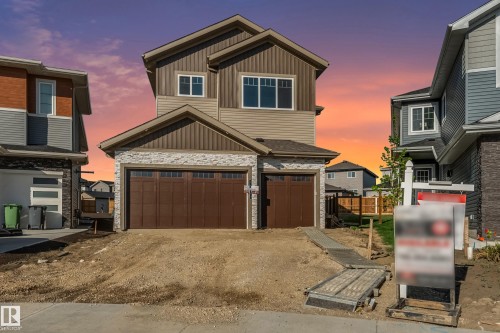 Contemporary residence featuring a two-car garage with wood-finish doors, horizontal siding, stone veneer accents, and multiple windows - 4015 39 Street, Beaumont, AB - Outdoor