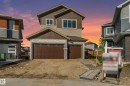 Contemporary residence featuring a two-car garage with wood-finish doors, horizontal siding, stone veneer accents, and multiple windows - 4015 39 Street, Beaumont, AB  - Outdoor 