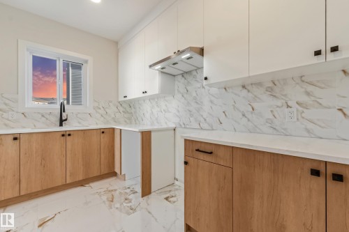 Modern kitchen featuring two-tone cabinetry with wood-finish lower cabinets and white upper cabinets - 4015 39 Street, Beaumont, AB - Indoor Photo Showing Kitchen