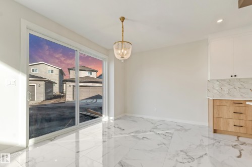 Spacious room featuring large format marble-look tile flooring, white walls, and a contemporary brass chandelier - 4015 39 Street, Beaumont, AB - Indoor