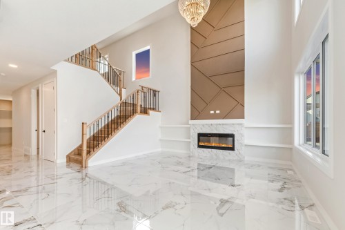 Grand living area featuring high ceilings, large format marble-look tile flooring, and an electric fireplace with a marble-look surround - 4015 39 Street, Beaumont, AB - Indoor Photo Showing Other Room With Fireplace