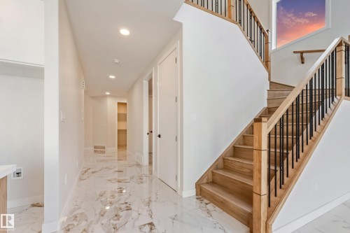 Open staircase with natural wood treads and risers, black metal balusters, and a matching wood handrail - 4015 39 Street, Beaumont, AB - Indoor Photo Showing Other Room