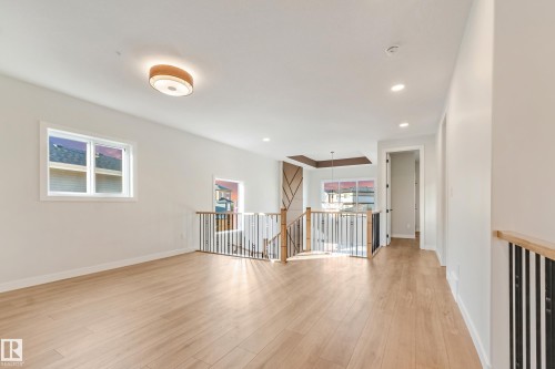 Spacious landing featuring light wood-finish flooring, white walls, and a contemporary flush-mount ceiling light - 4015 39 Street, Beaumont, AB - Indoor Photo Showing Other Room