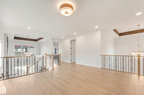 Open concept loft area featuring light wood-finish flooring, white walls, and a contemporary flush-mount ceiling light - 4015 39 Street, Beaumont, AB - Indoor Photo Showing Other Room