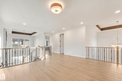 Open concept loft area featuring light wood-finish flooring, white walls, and a contemporary flush-mount ceiling light - 