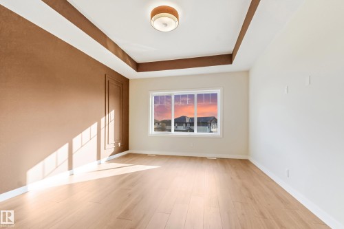 Spacious room featuring wood-finish flooring, a tray ceiling, and a prominent window - 4015 39 Street, Beaumont, AB - Indoor Photo Showing Other Room