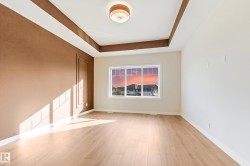 Spacious room featuring wood-finish flooring, a tray ceiling, and a prominent window - 