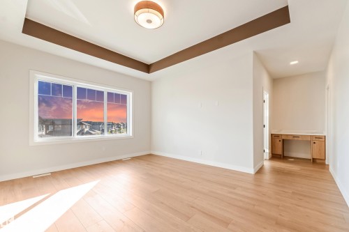 Spacious room featuring a large multi-pane window, tray ceiling with accent trim, recessed lighting, and wood-finish flooring - 4015 39 Street, Beaumont, AB - Indoor Photo Showing Other Room