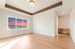 Spacious room featuring a large multi-pane window, tray ceiling with accent trim, recessed lighting, and wood-finish flooring - 
