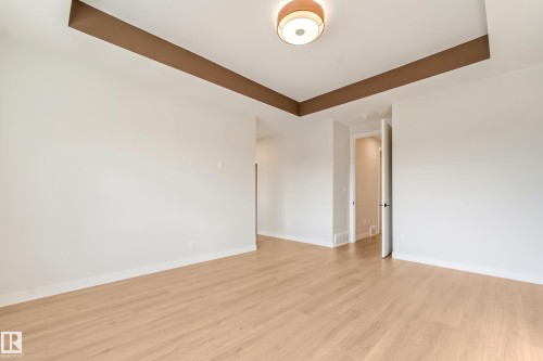 Spacious room featuring light wood-finish flooring, white walls, and a tray ceiling with a contrasting brown accent - 4015 39 Street, Beaumont, AB - Indoor Photo Showing Other Room