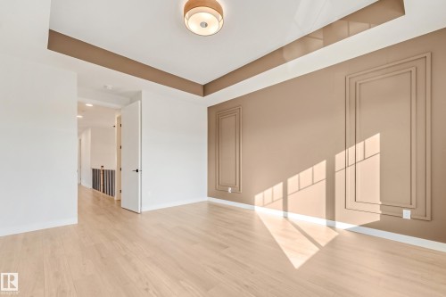 Spacious room featuring light wood-finish flooring, a contemporary ceiling fixture, and decorative wall paneling - 4015 39 Street, Beaumont, AB - Indoor Photo Showing Other Room
