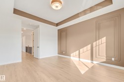 Spacious room featuring light wood-finish flooring, a contemporary ceiling fixture, and decorative wall paneling - 
