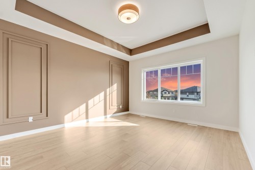 Spacious room featuring wood-finish flooring, a tray ceiling with a flush-mount light fixture, and a large window - 4015 39 Street, Beaumont, AB - Indoor Photo Showing Other Room