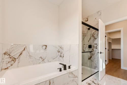 Soaking tub and shower combination featuring black fixtures, white and brown marble-look tile, and a glass shower enclosure - 4015 39 Street, Beaumont, AB - Indoor Photo Showing Bathroom