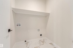 Dedicated laundry area featuring a built-in shelf, marble-patterned tile flooring, baseboard trim, and a contemporary door with matte black hardware - 