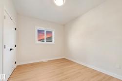 Bright room featuring light wood-finish flooring, white walls, and a single window with white trim - 