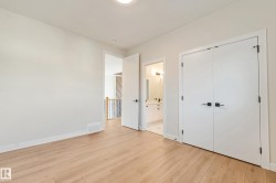 Light wood-finish flooring extending into the hallway, featuring white walls, white trim, and a white bi-fold closet door with matte black hardware - 