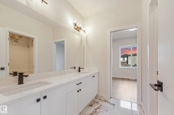 Dual vanity with matte black fixtures, white cabinetry, a light-toned countertop, and reflective flooring - 