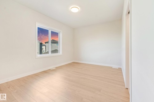 Bright room featuring wood-finish flooring, a double-pane window, flush-mount ceiling light, and neutral wall tones - 4015 39 Street, Beaumont, AB - Indoor Photo Showing Other Room