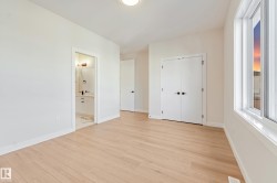 Spacious room featuring light wood-finish flooring, white walls, and a recessed ceiling light - 