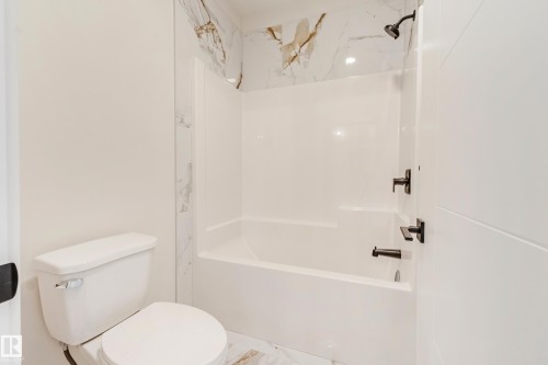 Bathroom featuring a white bathtub and shower combination with black fixtures, complemented by a white toilet - 4015 39 Street, Beaumont, AB - Indoor Photo Showing Bathroom