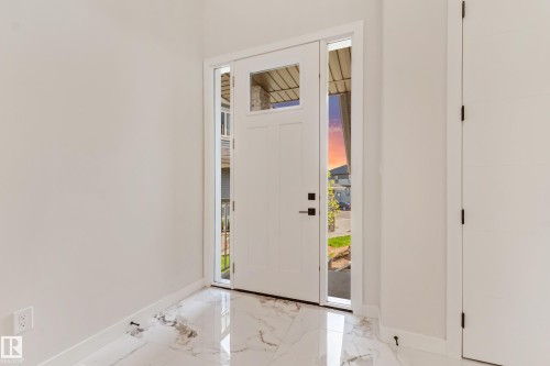 Entryway featuring a white door with transom and sidelight windows, black hardware, and polished marble-look flooring - 4015 39 Street, Beaumont, AB - Indoor Photo Showing Other Room