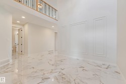 Spacious interior featuring high ceilings, large-format tile flooring, decorative wall molding, and a second-story balcony with an iron railing - 