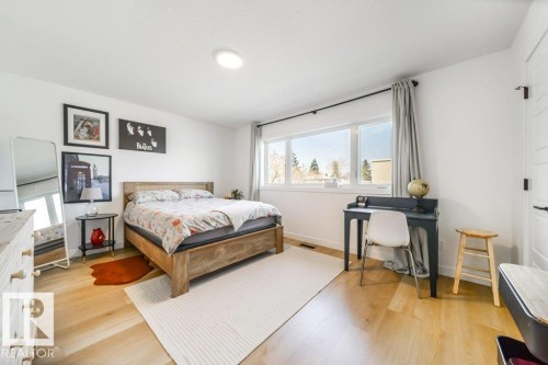 Bright bedroom featuring light wood-finish flooring, white walls, and a large multi-pane window - 11303 111 Avenue, Edmonton, AB - Indoor Photo Showing Bedroom