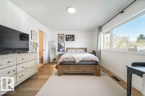 Hardwood-style flooring throughout this room, featuring a large window with exterior views - 11303 111 Avenue, Edmonton, AB - Indoor Photo Showing Bedroom