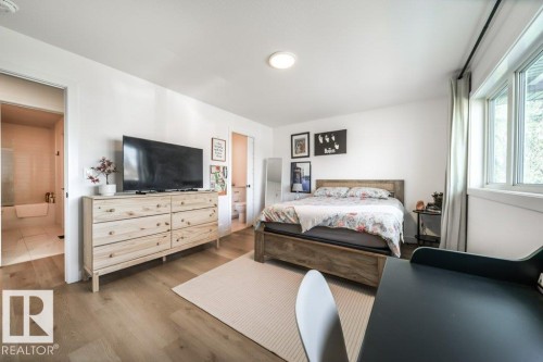 Bright bedroom featuring wood-finish flooring and a large window - 11303 111 Avenue, Edmonton, AB - Indoor Photo Showing Bedroom