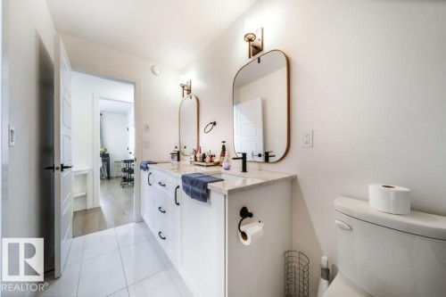 Double vanity featuring white cabinetry with black hardware, stone countertop, two rectangular mirrors, and wall-mounted sconces - 11303 111 Avenue, Edmonton, AB - Indoor Photo Showing Bathroom