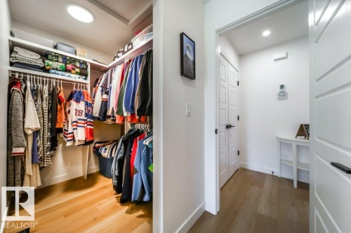 Walk-in closet featuring wood-finish flooring, built-in shelving, and hanging rods - 11303 111 Avenue, Edmonton, AB - Indoor With Storage