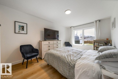 Bedroom featuring wood-finish flooring, a large window, a built-in ceiling light fixture, and white baseboards - 11303 111 Avenue, Edmonton, AB - Indoor Photo Showing Bedroom