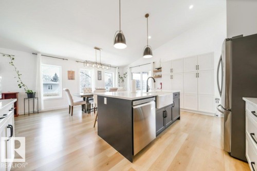 Open-concept kitchen featuring a large central island with a farmhouse sink, stainless steel appliances, and wood-finish flooring - 11303 111 Avenue, Edmonton, AB - Indoor Photo Showing Kitchen With Stainless Steel Kitchen With Upgraded Kitchen