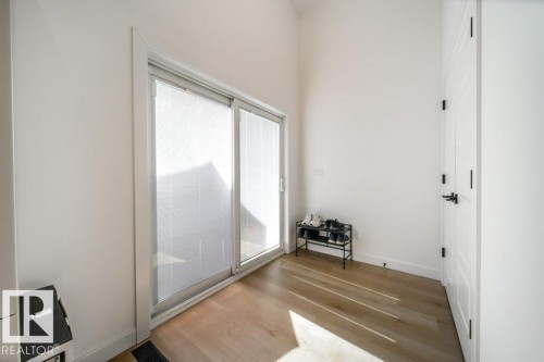Sliding glass doors featuring horizontal blinds, wood-finish flooring, white walls, and a white paneled door with black hardware - 11303 111 Avenue, Edmonton, AB - Indoor Photo Showing Other Room