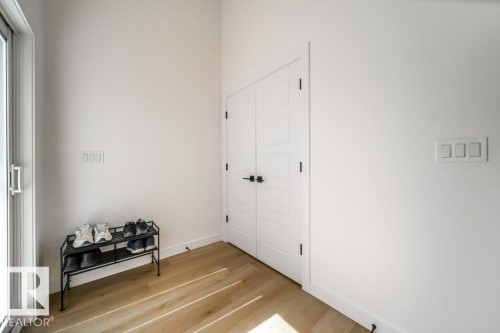 Double panel doors with matte black hardware, light wood-finish flooring, and crisp white walls - 11303 111 Avenue, Edmonton, AB - Indoor Photo Showing Other Room