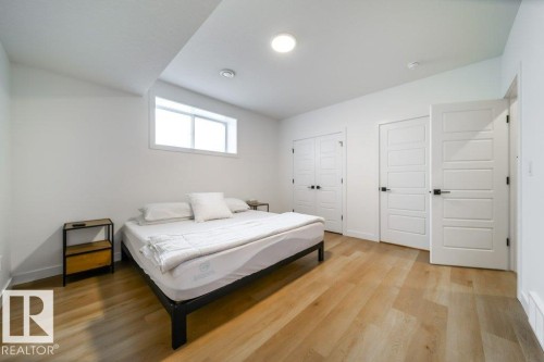 Room featuring light wood-finish flooring, white walls, and a multi-panel interior door with matte black hardware - 11303 111 Avenue, Edmonton, AB - Indoor Photo Showing Bedroom