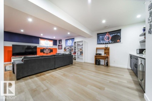 Spacious room featuring light wood-finish flooring, recessed lighting, a built-in wet bar with dark cabinetry, and white shelving - 11303 111 Avenue, Edmonton, AB - Indoor