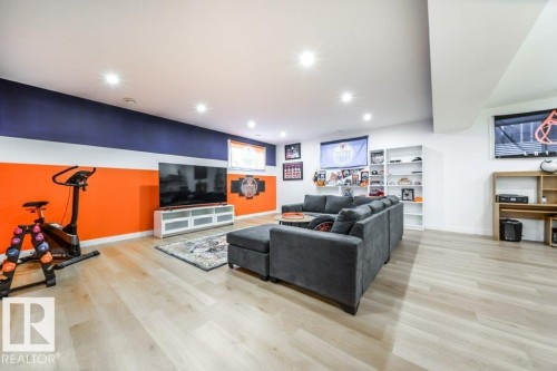 Spacious recreation room featuring light wood-finish flooring, recessed lighting, and a built-in shelving unit - 11303 111 Avenue, Edmonton, AB - Indoor